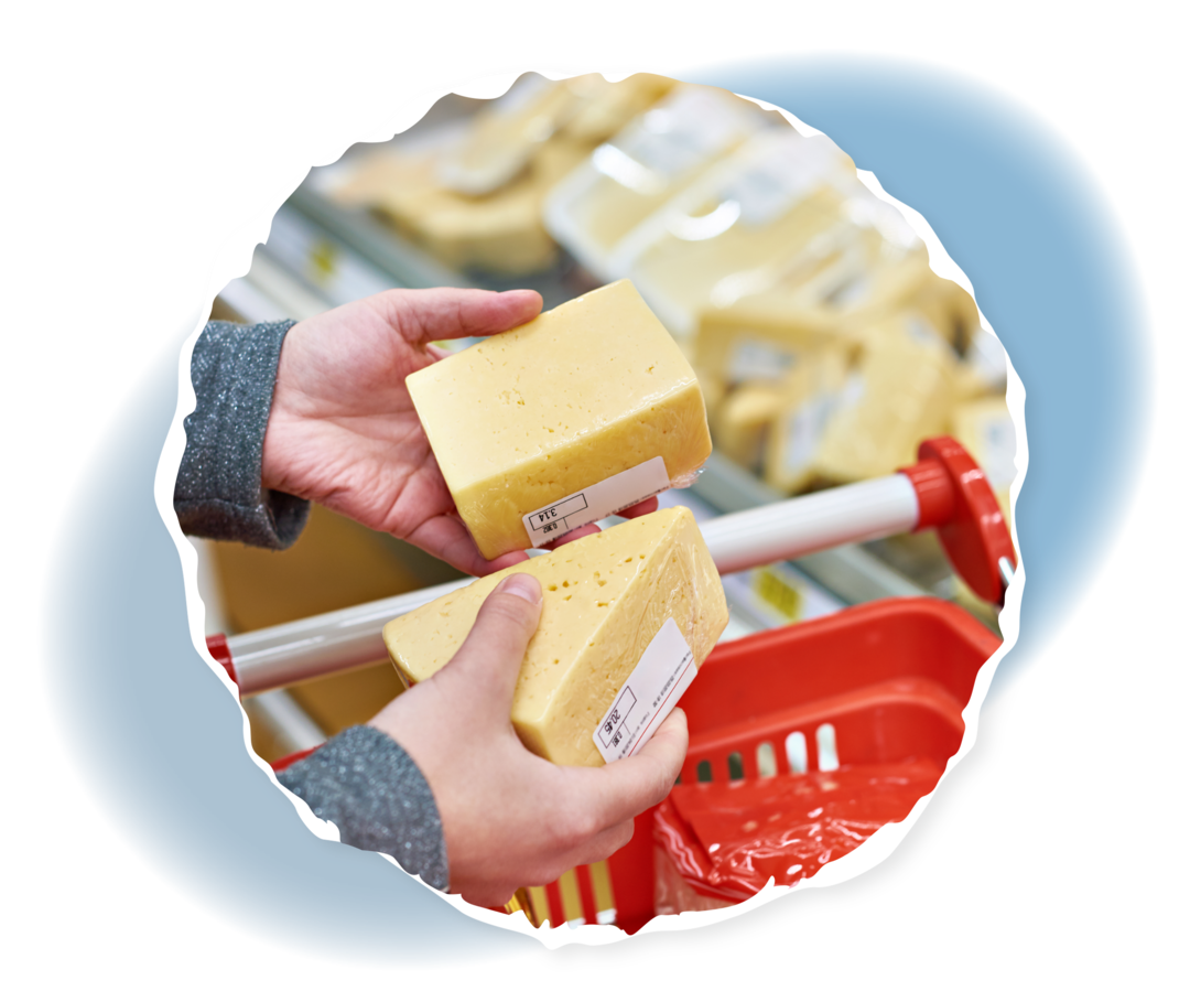 Eine Person hält an der Käsetheke zwei Stücke Käse in der Hand.