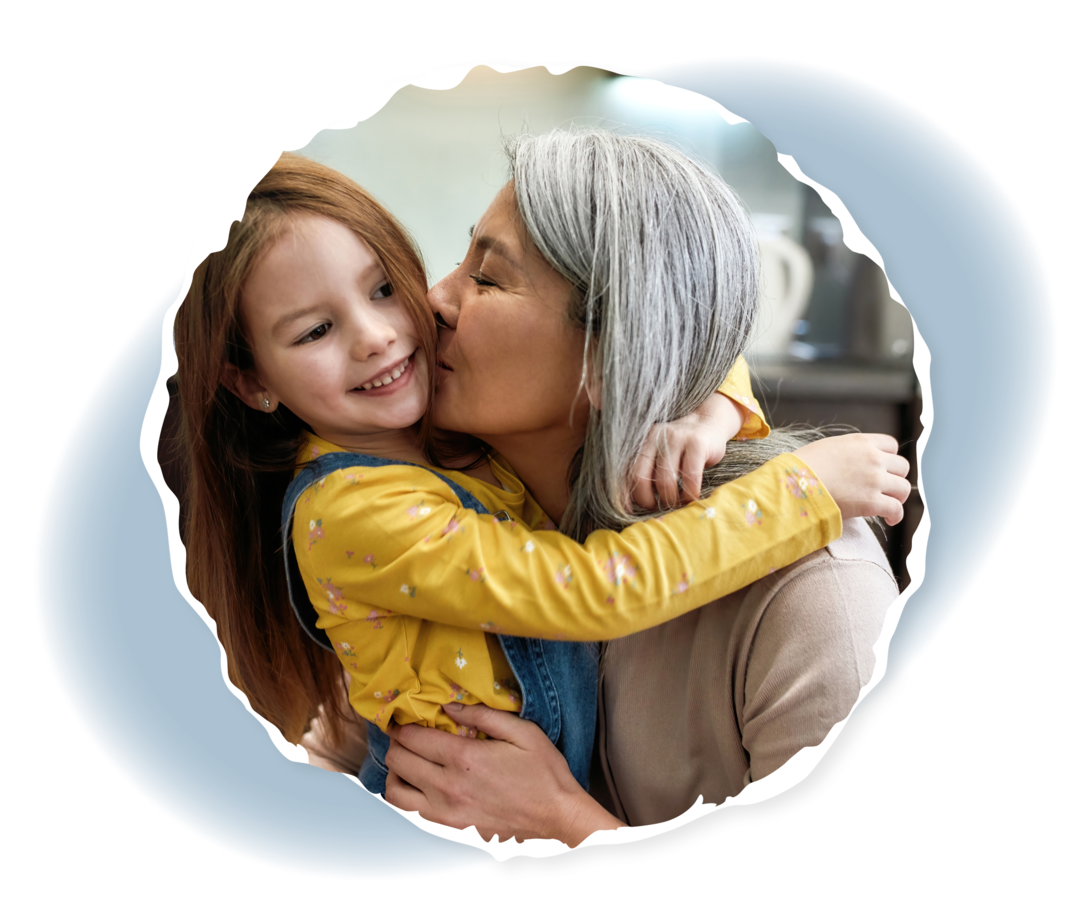 Eine ältere Frau küsst ein junges Mädchen auf die Wange.